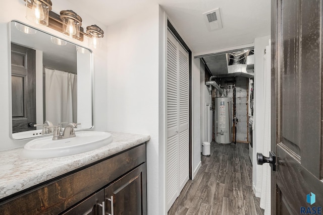 full bathroom with visible vents, wood finished floors, gas water heater, a closet, and vanity
