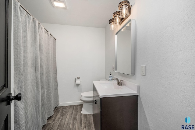 bathroom with visible vents, baseboards, toilet, wood finished floors, and vanity