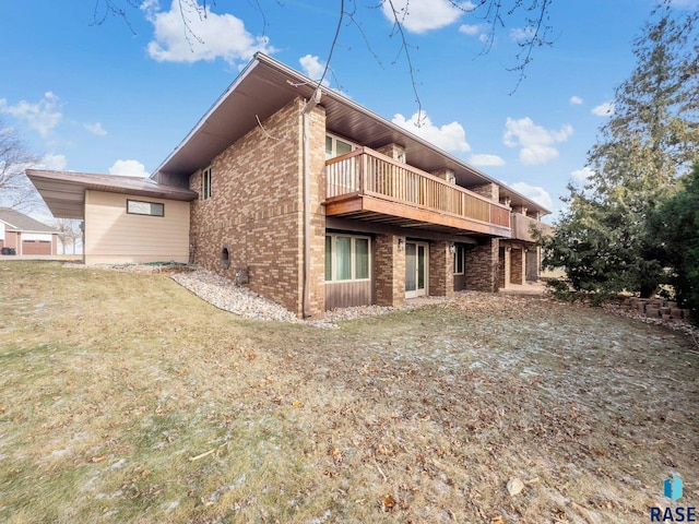 rear view of house featuring a yard and brick siding