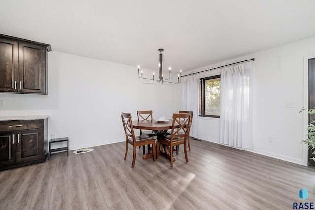 dining room featuring an inviting chandelier, baseboards, and light wood-style floors