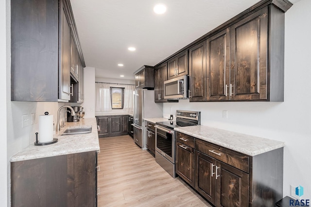 kitchen with a sink, recessed lighting, stainless steel appliances, light wood-style floors, and dark brown cabinetry
