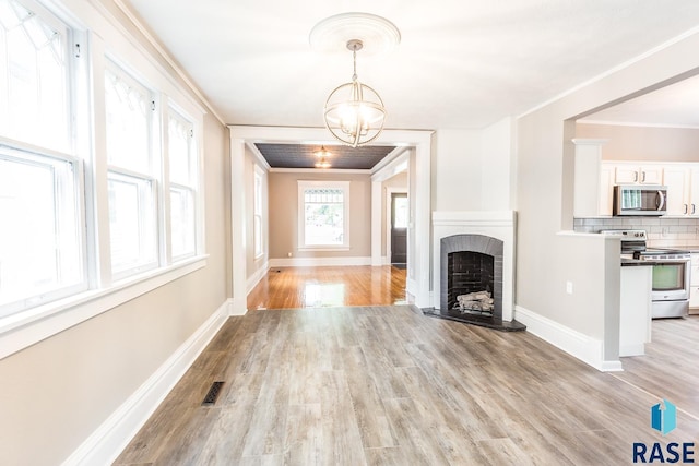 unfurnished living room featuring visible vents, light wood-style floors, ornamental molding, and a fireplace