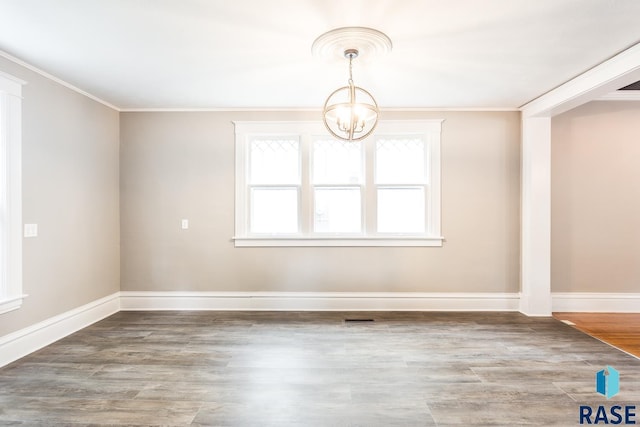 unfurnished dining area with an inviting chandelier, wood finished floors, baseboards, and ornamental molding