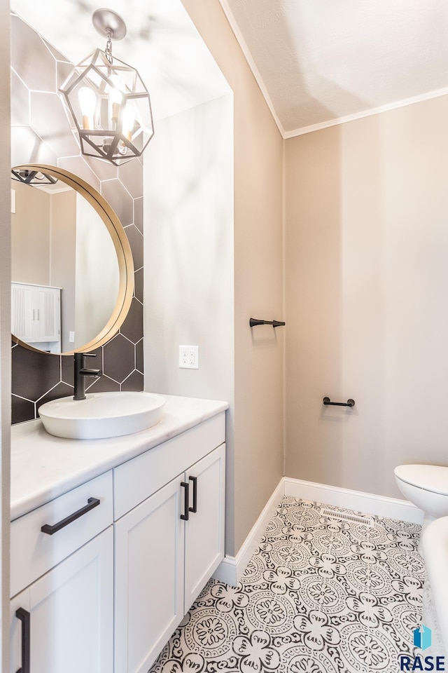 bathroom featuring ornamental molding, tasteful backsplash, tile patterned flooring, baseboards, and vanity