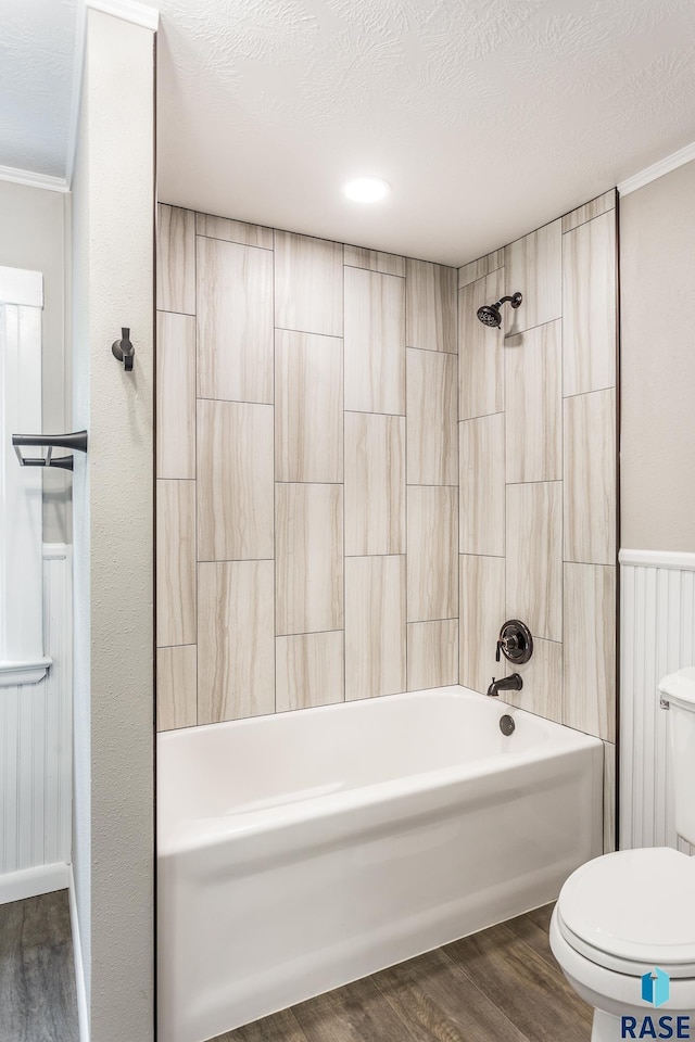 bathroom featuring a textured ceiling, toilet, wood finished floors, and shower / washtub combination