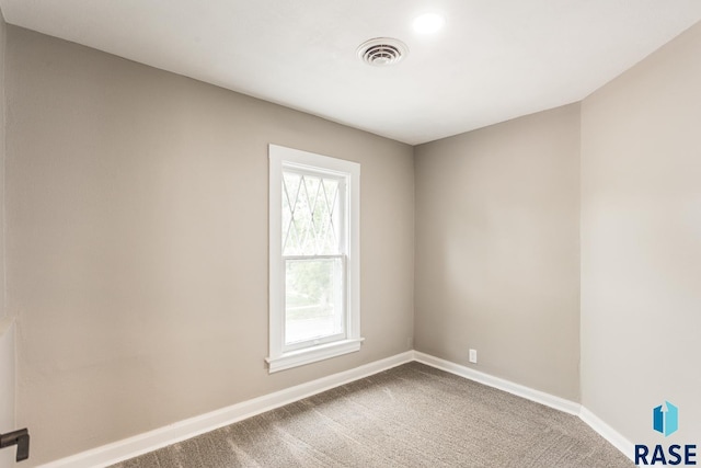 carpeted spare room featuring visible vents and baseboards