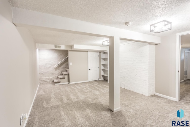 finished below grade area featuring stairway, visible vents, carpet floors, and a textured ceiling