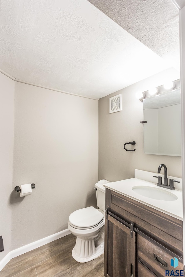 bathroom featuring vanity, toilet, wood finished floors, and visible vents