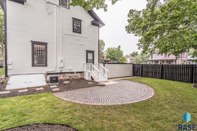 rear view of house with a yard, central air condition unit, a patio, and fence