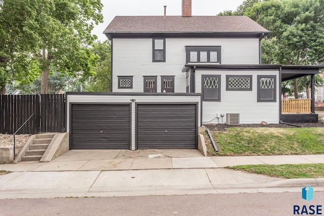 view of front of home featuring an attached garage, fence, central air condition unit, a chimney, and driveway