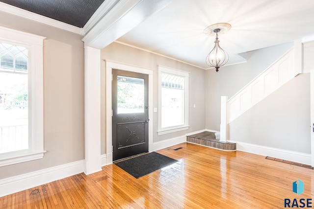 foyer entrance with baseboards, ornamental molding, stairs, and hardwood / wood-style flooring