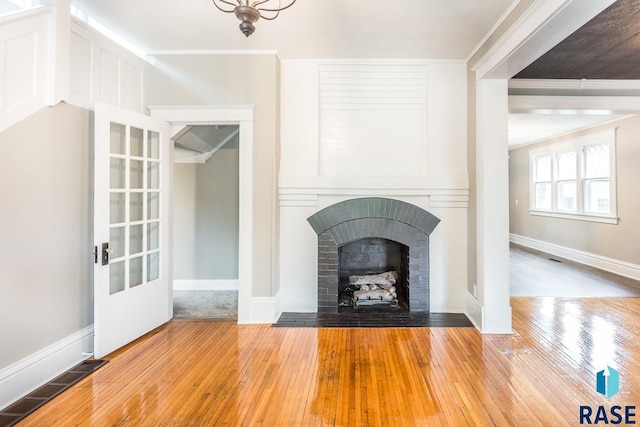 unfurnished living room with hardwood / wood-style flooring, a fireplace, visible vents, and ornamental molding