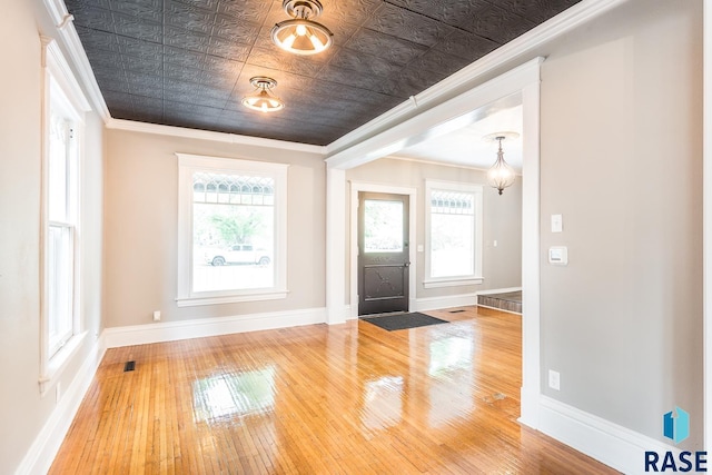 foyer featuring wood-type flooring, baseboards, an ornate ceiling, and ornamental molding