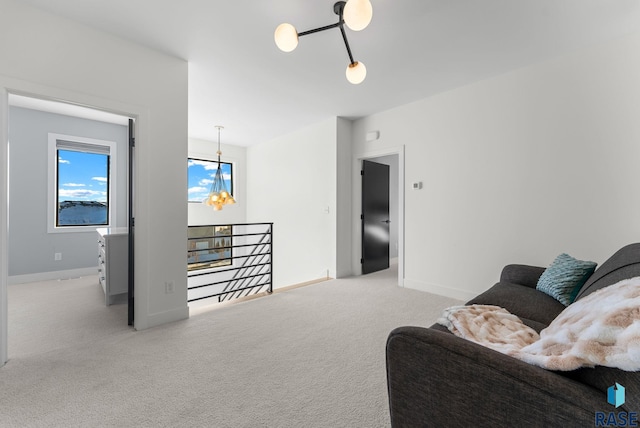 carpeted living room with a chandelier and baseboards