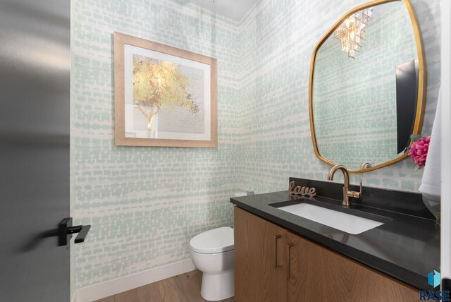 half bathroom with vanity, toilet, and wood finished floors