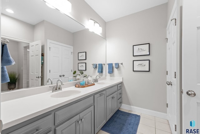 bathroom with tile patterned floors, double vanity, baseboards, and a sink