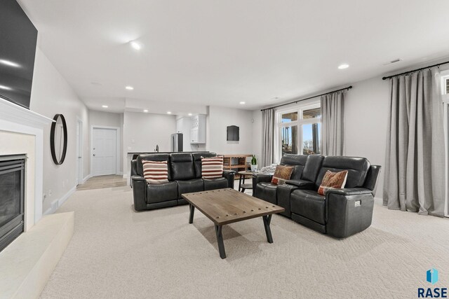 living room with a high end fireplace, recessed lighting, light colored carpet, and baseboards