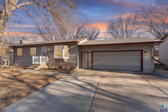 ranch-style home featuring a garage, roof with shingles, concrete driveway, and a chimney