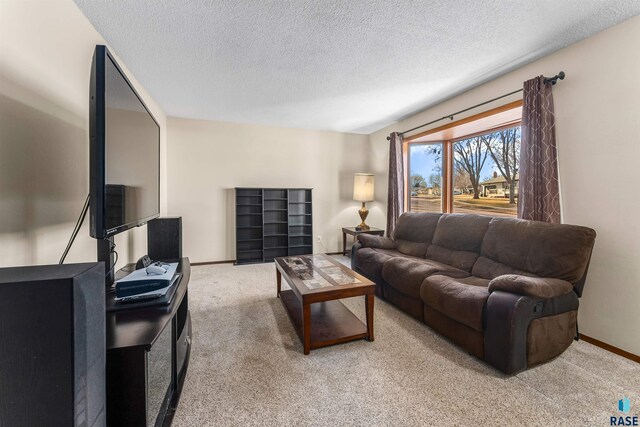 living area with baseboards, light colored carpet, and a textured ceiling