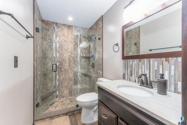 bathroom with a shower stall, a textured ceiling, toilet, and vanity