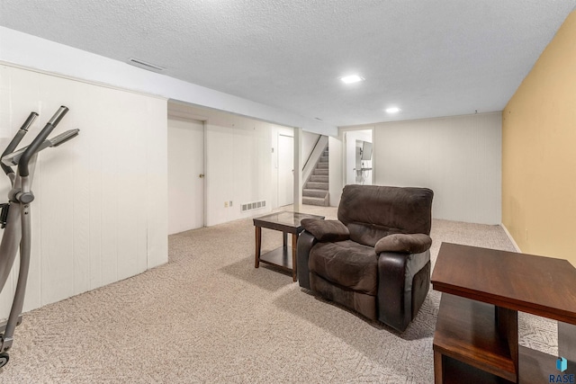 living area with visible vents, carpet floors, a textured ceiling, and stairs