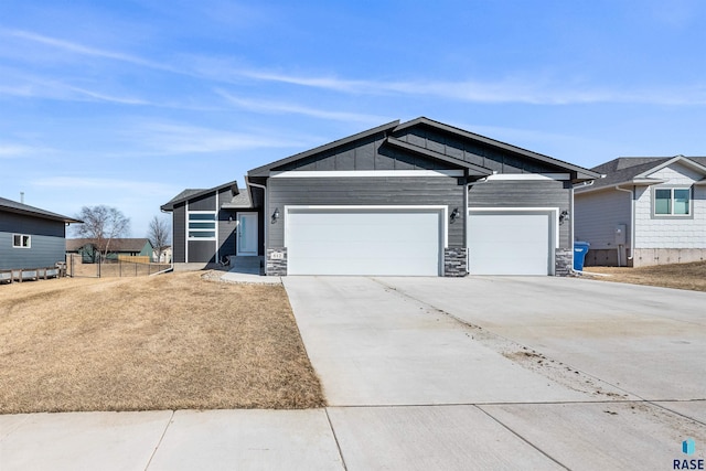 view of front of house featuring stone siding, board and batten siding, driveway, and a garage