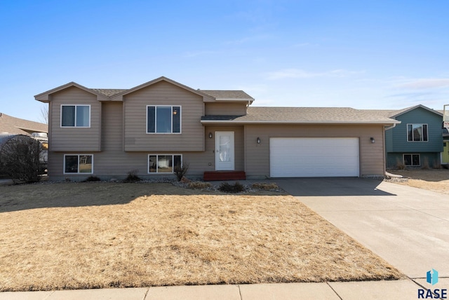 tri-level home with concrete driveway, a garage, and a shingled roof