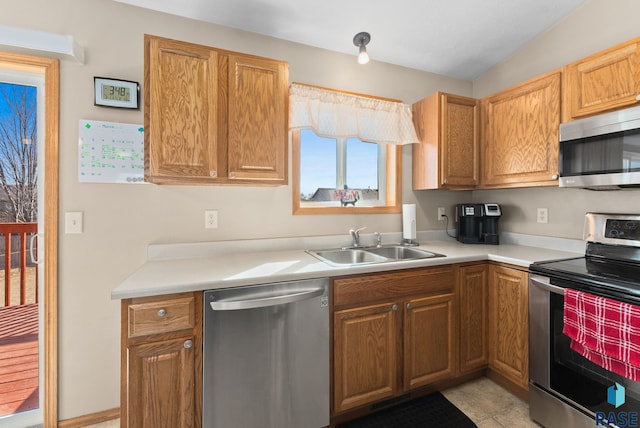 kitchen with light countertops, brown cabinetry, appliances with stainless steel finishes, and a sink