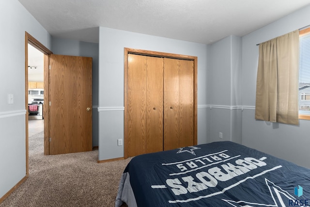 bedroom with a closet, carpet floors, a textured ceiling, and baseboards