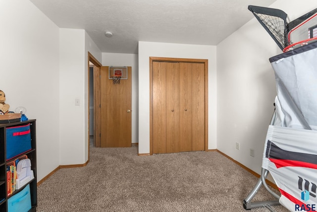 bedroom featuring a closet, baseboards, carpet, and a textured ceiling