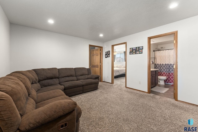 carpeted living area with recessed lighting, a textured ceiling, and baseboards