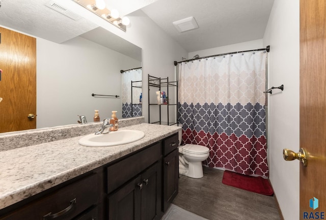 full bathroom with visible vents, toilet, vanity, wood finished floors, and a textured ceiling