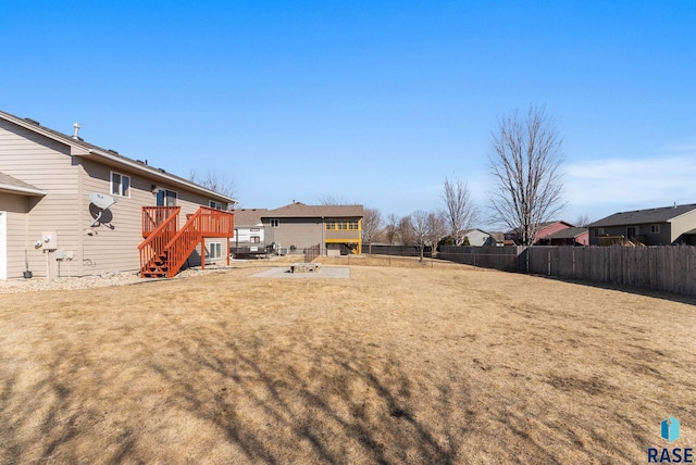 view of yard featuring stairway, a wooden deck, a fenced backyard, and a residential view