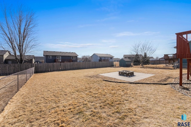 view of yard featuring a patio area, a fire pit, a residential view, and a fenced backyard