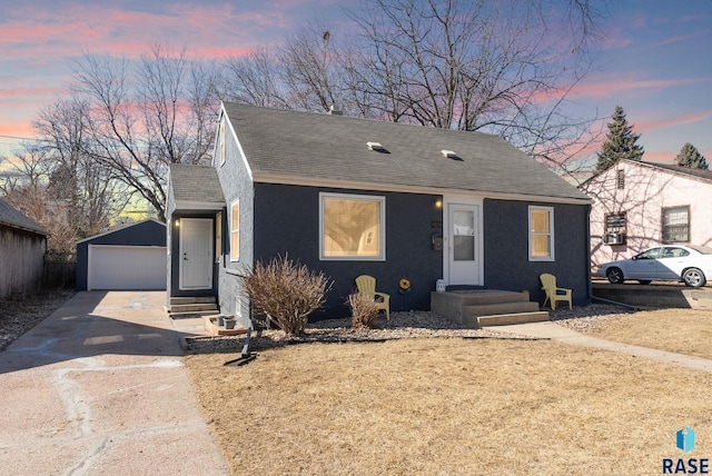 bungalow-style house featuring an outbuilding, stucco siding, a shingled roof, and a detached garage