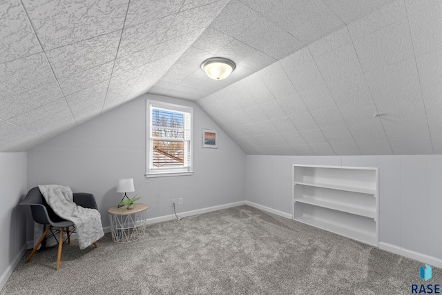 unfurnished room featuring built in features, baseboards, carpet floors, vaulted ceiling, and a textured ceiling