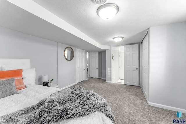 carpeted bedroom featuring a textured ceiling and baseboards