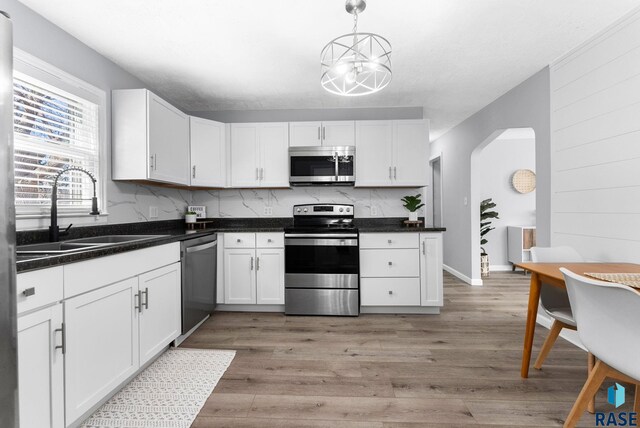 kitchen with light wood-style flooring, appliances with stainless steel finishes, white cabinetry, and a sink