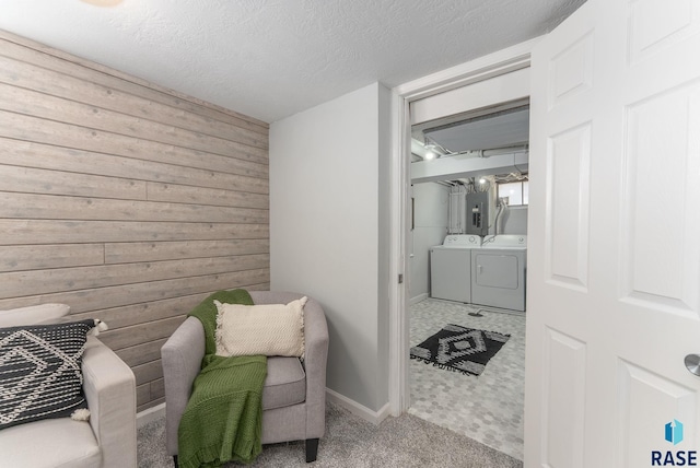 sitting room with carpet floors, washing machine and clothes dryer, electric panel, wood walls, and a textured ceiling