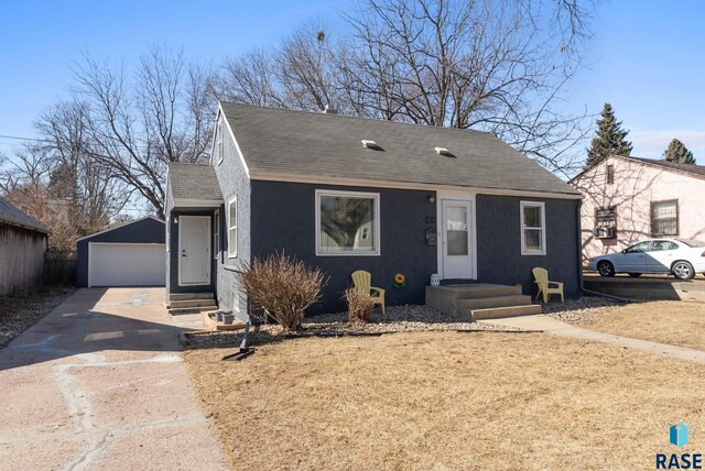 bungalow-style home featuring an outbuilding, stucco siding, a garage, and a shingled roof