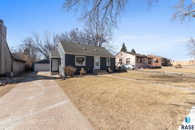 view of front facade with an outbuilding, a detached garage, and a front yard