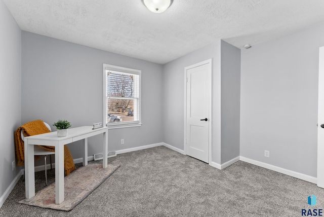 unfurnished office with visible vents, baseboards, a textured ceiling, and carpet floors