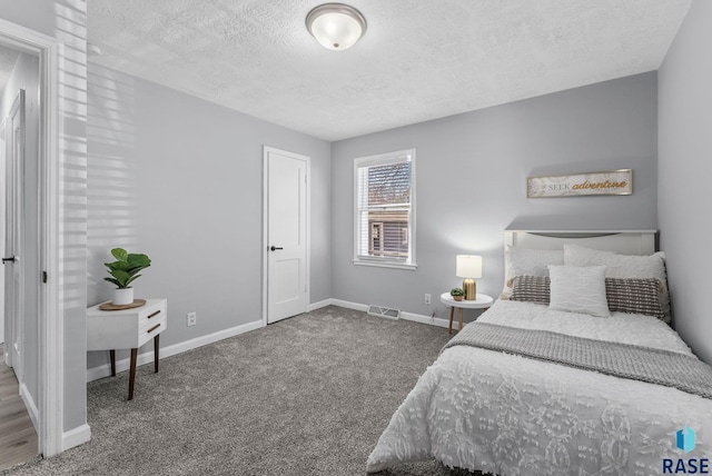 bedroom with baseboards, visible vents, carpet floors, and a textured ceiling