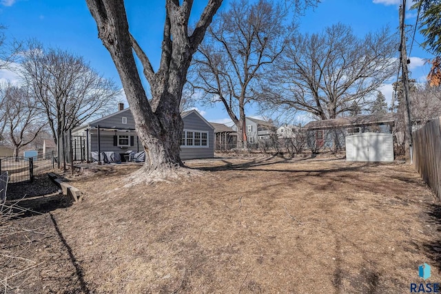 view of yard with an outdoor structure, fence, and a shed