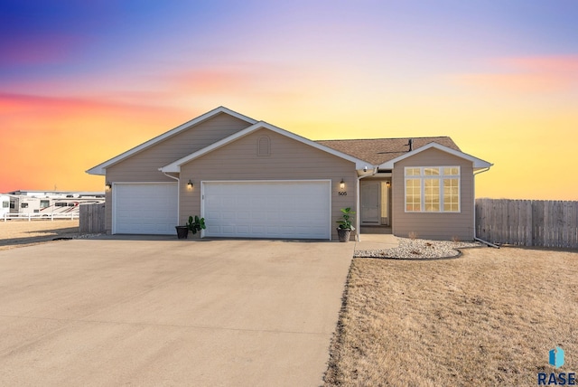 ranch-style home featuring concrete driveway, an attached garage, and fence