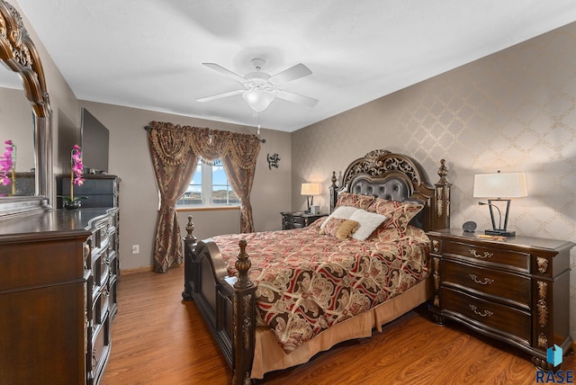 bedroom with wallpapered walls, a ceiling fan, and wood finished floors