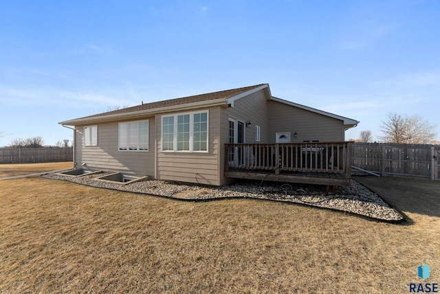 back of property with a lawn, a deck, and fence