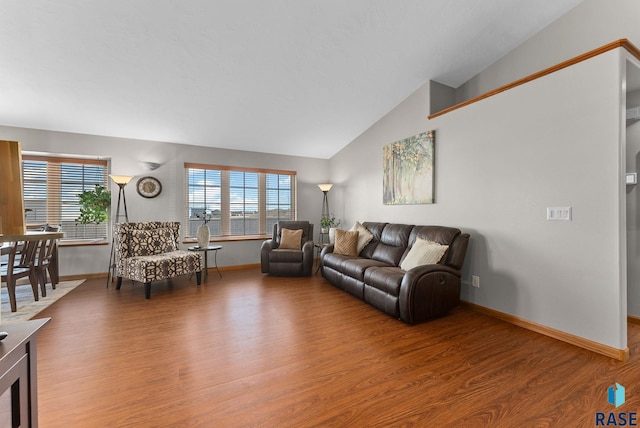 living area featuring baseboards, lofted ceiling, and wood finished floors