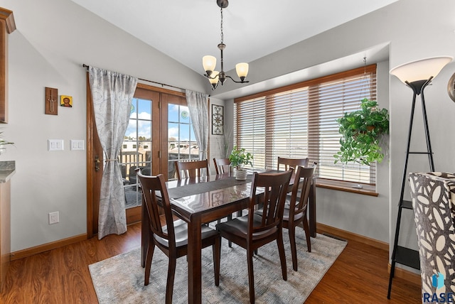 dining room featuring vaulted ceiling, a notable chandelier, wood finished floors, and baseboards