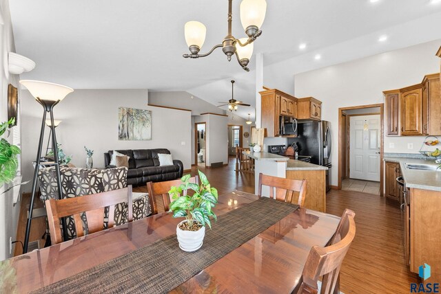 dining space featuring recessed lighting, ceiling fan with notable chandelier, lofted ceiling, and wood finished floors